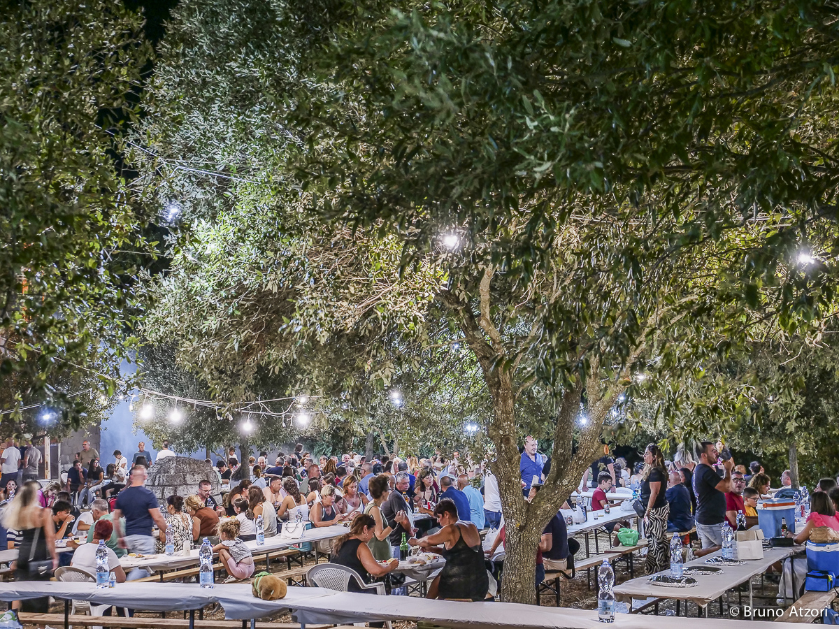 CENA – PERSONE AI TAVOLI
L'ultima tappa è quella della convivialità: lunghe tavolate condivise, sapori della cucina locale e vino per concludere una giornata dedicata alla cultura e alle tradizioni del territorio.